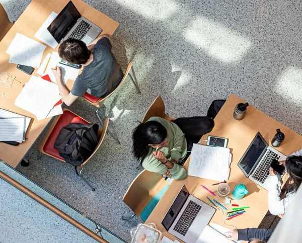 aerial of kids studying with laptops and papers