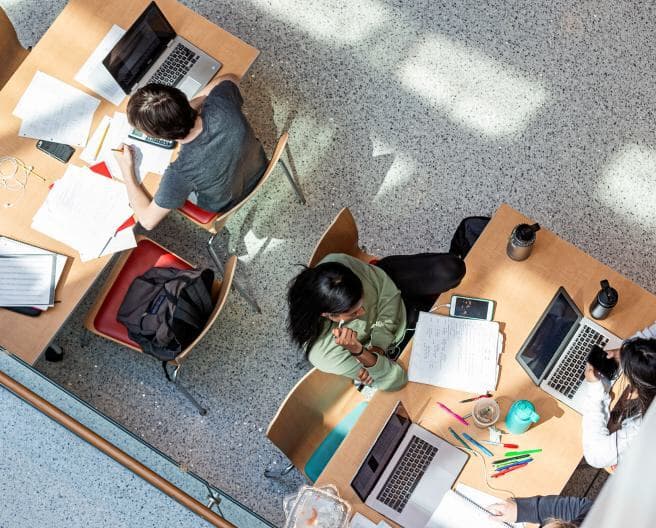 aerial of kids studying with laptops and papers